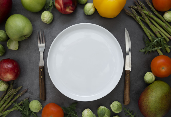 Healthy foods or diet concept. Empty round plate with different fruits and vegetables arround. Flat lay.